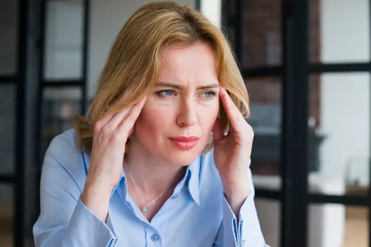 A woman pressing her temples while trying to concentrate