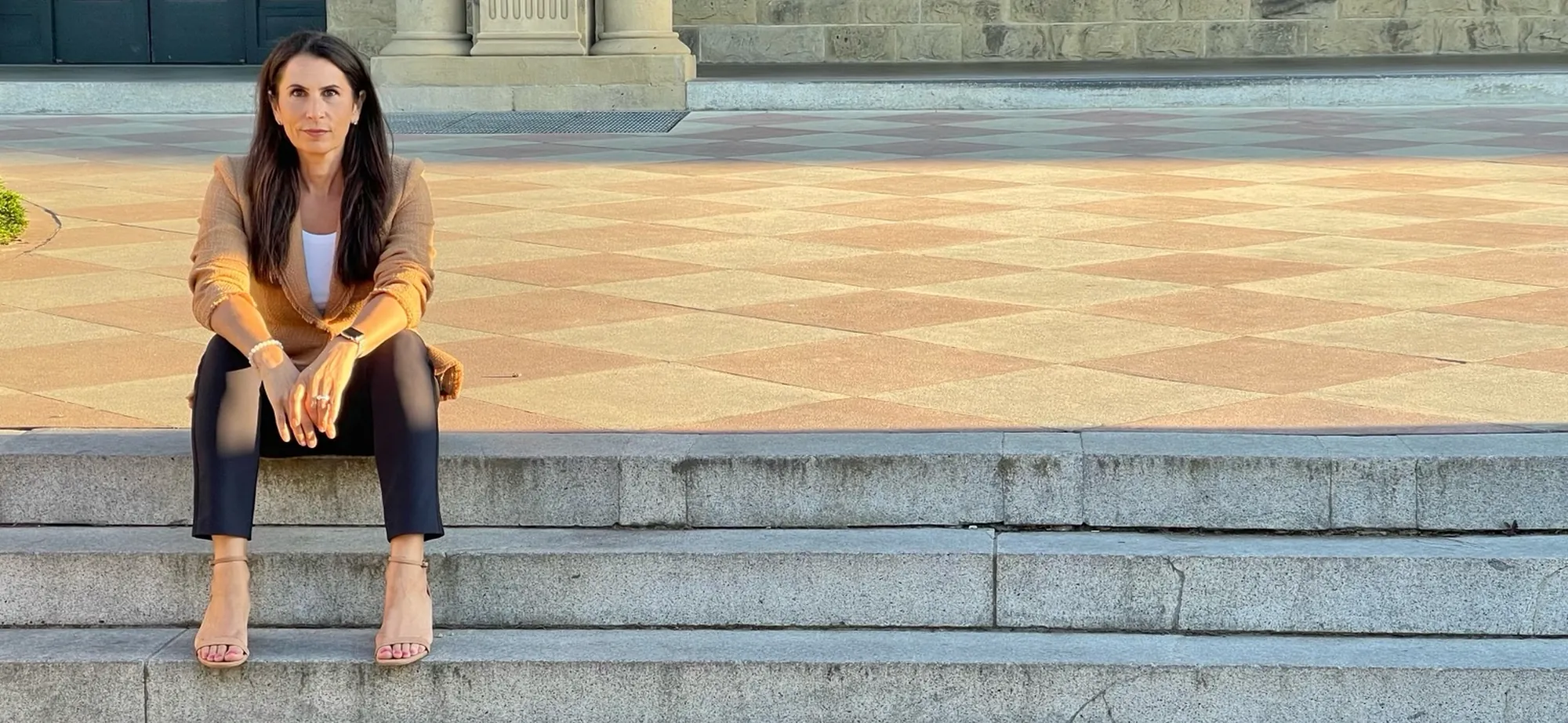 Dr. Samia McCully, ND, seated on sunlit stone steps